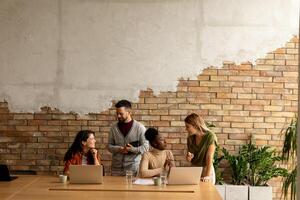 Young multiethnic startup team working by the brick wall in the industrial style office photo