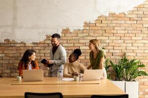 Young multiethnic startup team working by the brick wall in the industrial style office photo