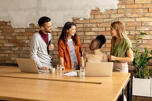 Young multiethnic startup team working by the brick wall in the industrial style office photo