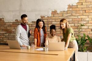 Young multiethnic startup team working by the brick wall in the industrial style office photo