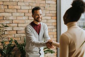 Young multiethnic business couple handshaking in the modern office photo