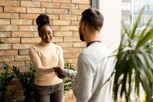 Young multiethnic business couple handshaking in the modern office photo