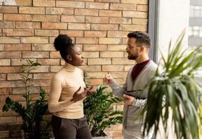 Young multiethnic business couple with digital tablet standing and discussing in the modern office photo