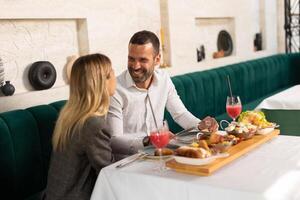 joven Pareja teniendo almuerzo y Bebiendo Fresco exprimido jugo en el restaurante foto