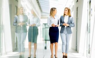 Two young business women walking and discussing in the office hallway photo