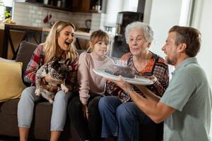 jubiloso familia celebrando abuelas cumpleaños con pastel en un acogedor vivo habitación foto