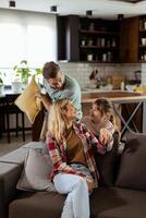 Playful family pillow fight in a cozy living room at dusk photo