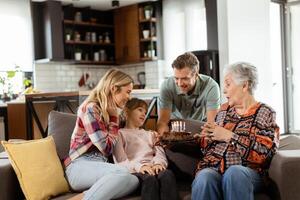 jubiloso familia celebrando abuelas cumpleaños con pastel en un acogedor vivo habitación foto