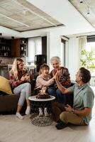 jubiloso familia celebrando abuelas cumpleaños con pastel en un acogedor vivo habitación foto