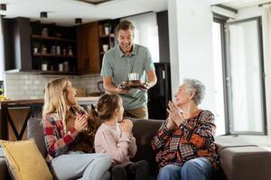 Joyous Family Celebrating Grandmothers Birthday With Cake in a Cozy Living Room photo