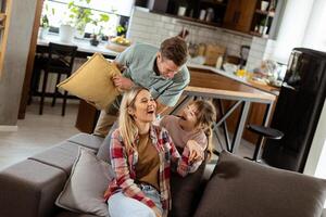 Playful family pillow fight in a cozy living room at dusk photo