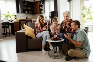 jubiloso familia celebrando abuelas cumpleaños con pastel en un acogedor vivo habitación foto