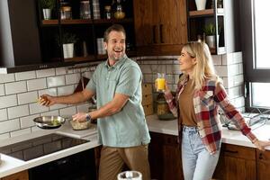 Man and woman sharing a laugh as they cook in a cozy, well-organized kitchen photo