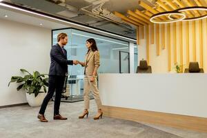 Warm Handshake Between Colleagues In Modern Office Lobby Under Ambient Lighting photo