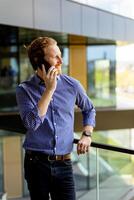 Professional Gentleman Engages in a Serious Conversation on His Smartphone at During a Sunny Afternoon photo