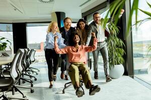 Joyful Office Colleagues Engage in a Playful Chair Race on a Sunny Afternoon. photo