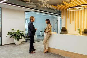 Professional Colleagues Engage in Conversation by the Reception in a Modern Office Setting photo