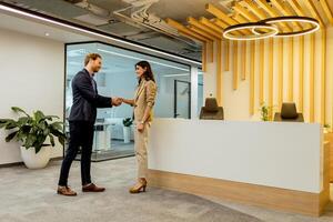 Warm Handshake Between Colleagues In Modern Office Lobby Under Ambient Lighting photo