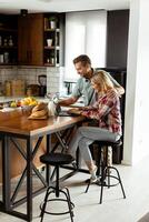 Cheerful couple enjoys a light-hearted moment in their sunny kitchen, working on laptop surrounded by a healthy breakfast photo