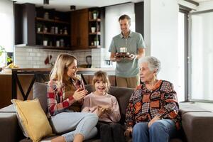 Joyous Family Celebrating Grandmothers Birthday With Cake in a Cozy Living Room photo