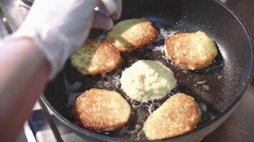 voorbereiding van gouden krokant aardappel pannekoeken in een frituren pan. groente beignets. video