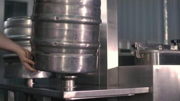 un joven masculino cervecero lavados y esteriliza cerveza barriles utilizando un automático cerveza barrilete esterilización máquina. de cerca video