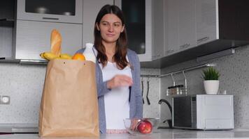 comida entrega hogar. en línea compra. en línea tecnología. sano estilo de vida. un joven mujer toma comida desde un paquete mientras en el cocina video