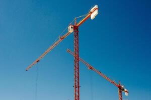 amarillo industrial grúas trabajando en construcción sitio en contra azul cielo foto