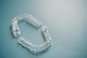 Invisalign braces or invisible retainer on blue background photo