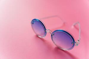 Different stylish sunglasses on pink background photo