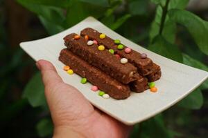 Chocolate cookies with colorful candies on a wooden plate in hand photo