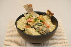 fish with rice and vegetables in a bowl on a wooden table. photo