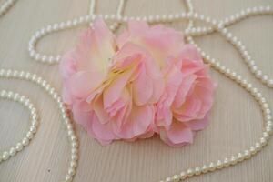 pink rose with pearl necklace on wood background, soft focus. photo