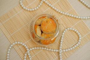 Cookies in a glass jar on a bamboo mat with pearls photo