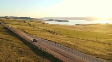 Aerial. Car driving on a dirt road against the backdrop of a beautiful coastline video