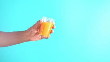 halten ein Glas von Orange Saft gegen Farbe Hintergrund video