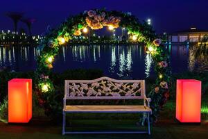 Decorative bench with garlands in a night park against the backdrop of a pond. photo