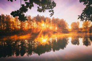 amanecer en un lago o río con un cielo reflejado en el agua, abedul arboles en el apuntalar y el rayos de sol rotura mediante ellos y niebla en otoño. estética de Clásico película. foto