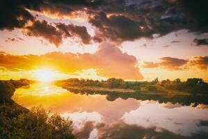 Sunrise or sunset on a lake or river with cloudy sky reflection in the water in summertime. Aesthetics of vintage film. photo