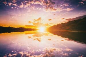 Sunrise or sunset on a lake or river with cloudy sky reflection in the water in summertime. Aesthetics of vintage film. photo