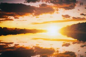 Sunrise or sunset on a lake or river with cloudy sky reflection in the water in summertime. Aesthetics of vintage film. photo