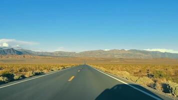 Desert Highway Leading to Mountains, Open desert road leading straight towards distant mountains under a clear sky. video