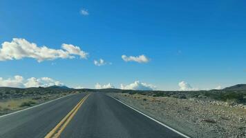 aberto estrada dentro a deserto, uma deserta rodovia alongar para dentro a horizonte debaixo uma grande azul céu com fofo nuvens. video