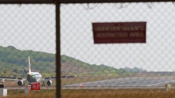 Phuket, Thailand - - Januar 26, 2023. Verkehrsflugzeug Verlangsamung runter, Landung, Spoiler hoch. boeing 737, HS-DB von nein Luft rollen zu das Runway beim Phuket Flughafen. Tafel hinter das Flughafen Zaun. video