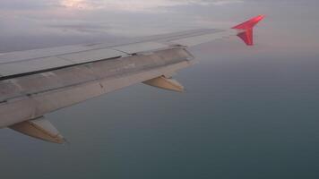 View from a plane window showing the wing of an aircraft soaring through the sky during flight. Travel concept video