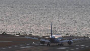 cinématique métrage de une passager avion en arrivant à le aéroport. lent vers le bas après atterrissage, spoilers en haut. mer Contexte. gens en train de regarder Avions de le rivage video