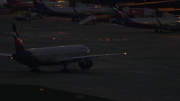 sochi, Rusia - julio 30, 2022. fuselaje ancho pasajero avión boeing 777 de aeroflot rodaje a el terminal a Sochi aeropuerto a noche. fila de aviones en el delantal en el noche video