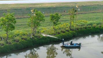 BANGKOK, THAILAND - JANUARY 20, 2023. A person operates a boat equipped with a water aeration system, creating a water spray to water plants. View from the window of the Miracle Suvarnabhumi Hotel video