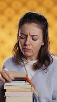 verticaal portret van vrouw browsen door stack van studieboeken, bijeenkomst informatie voor school- examen, geïsoleerd over- studio achtergrond. persoon zoeken vereist Cursus voor tentamen in stapel van boeken, camera b video