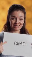 Vertical Woman holding message in hands urging people to read more, talking about importance of lecture, isolated over studio background. Bookworm promoting literacy concept, camera A video